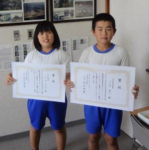 小学生が賞状を持った記念写真の画像