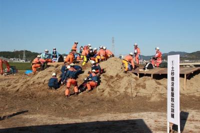 訓練用に土砂に埋めている家屋から要救助者を救出している画像
