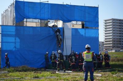 火災建物に見立てた訓練施設に隊員がはしごを架けて消火活動をしている画像