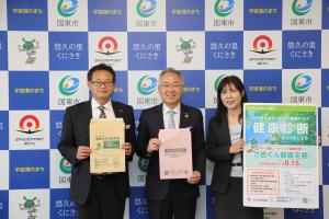 市長が寄贈していただいた封筒を持って、大分県信用組合の方と並んでいる写真です