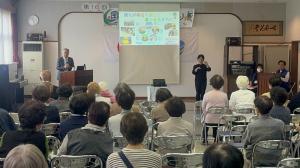 市長がプロジェクターを使用しながら講演しています