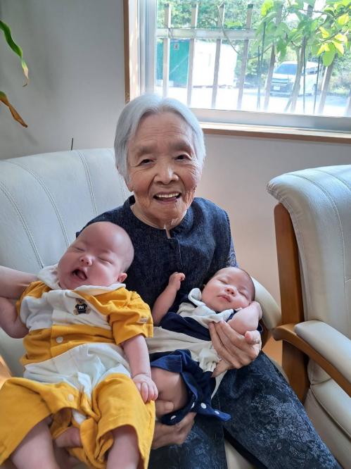 両手にひ孫をだっこするおばあさんの写真