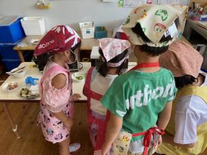 園児がピーマン料理を見ています